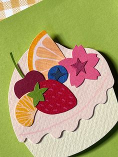 a piece of paper with fruit cut out of it sitting on top of a table