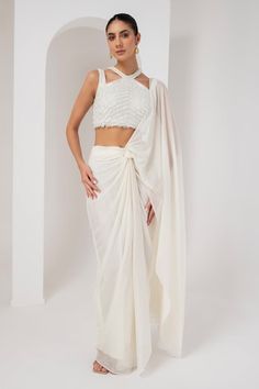 Ivory pre-draped saree crafted in metallic georgette. Paired with a sleeveless halter neck blouse with tonal crystal tassel embellishments. - Aza Fashions Halter Neck Blouse, Halter Neck Blouses, Tassel Blouse, Draped Saree, Drape Saree, Saree With Blouse, Sarees Online, Aza Fashion, Halter Neck