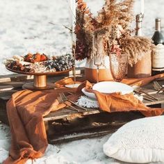 a table set up with plates and wine bottles on the beach for an outdoor dinner