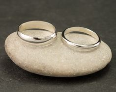 two wedding rings sitting on top of a rock