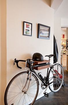 a bicycle parked against a wall in a room with pictures on the wall above it