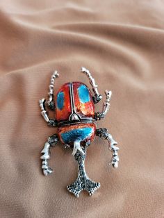 Red and blue enameled scarab brooch set in sterling silver. Multicolor Enamel Brooch Jewelry, Costume Jewelry Metal Brooches For Gifts, Metal Costume Jewelry Brooches For Gifts, Silver Enamel Pin For Gift, Red Enamel Brooch Pin, Red Enamel Brooch, Silver Cabochon Brooches Collectible, Silver Enamel Brooch Pin, Multicolor Cabochon Brooch As Gift