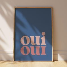 a blue and pink poster with the words oui oui on it in front of a white wall