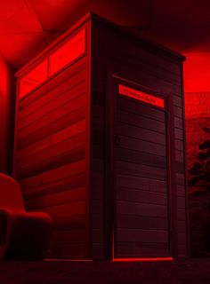 a red light shines on the side of a small room with a chair in it