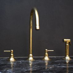 three golden faucets sitting on top of a black counter