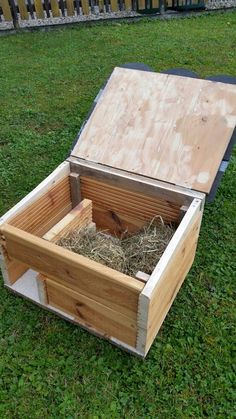 a wooden box with hay inside sitting on the grass