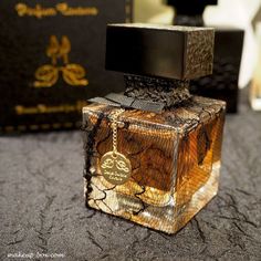 a bottle of perfume sitting on top of a table next to a black and gold box