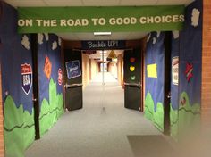 an entrance to a school hallway decorated with green and blue paper cutouts that read on the road to good choices