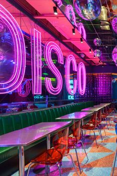 the disco bar is brightly lit and has neon lights on the ceiling, along with colorful chairs