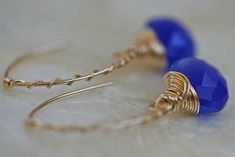 "Chalcedony open hoop earrings in cobalt blue and 14k gold fill. An elegant hand formed 14k gold filled arc shaped ear wire, made to look like a hoop earring, is wrapped with fine gauge 14k gold filled wire in a candy cane twist. Faceted cobalt blue chalcedony hangs from the ear wire. The heart shaped brioletts are lavishly wrapped in more 14k gold filled wire. Earrings hang approximately 1 1/2 \" (40mm) See more briolette dangle earrings here: http://www.etsy.com/shop/LHJewelryBoutique/search?s Blue Wire Wrapped Hoop Earrings For Gift, Blue Wire Wrapped Hoop Earrings As Gift, Handmade Blue 14k Gold-filled Earrings, Handmade Blue 14k Gold Filled Earrings, Handmade 14k Gold Filled Blue Earrings, Blue 14k Gold-filled Earrings, Blue Nickel-free 14k Gold-filled Hoop Earrings, Handmade Blue Hoop Earrings In 14k Gold Filled, Handmade Blue 14k Gold Filled Hoop Earrings