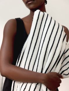 a woman is wrapped in a black and white striped towel while looking at the camera