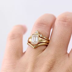 a woman's hand with a gold ring and an emerald stone on the band