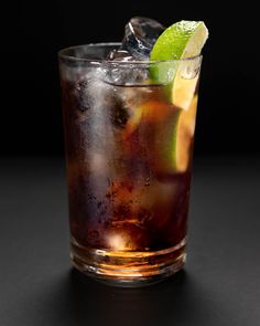 a close up of a drink in a glass with ice and lime on the rim