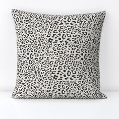 a black and white leopard print pillow sitting on top of a white table next to a wall