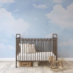 a baby's room with a crib, rocking horse and clouds painted on the wall