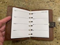 a hand holding an open leather planner book