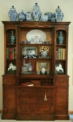 an antique china cabinet with blue and white vases on top