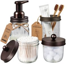 three glass jars with toothbrushes and soap in them