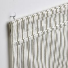 a striped curtain hanging on the wall next to a white and green stripped bed sheet