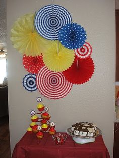 a table topped with lots of paper umbrellas next to a wall covered in decorations