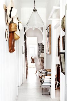 the hallway is decorated in white and has lots of hats hanging on the wall above it