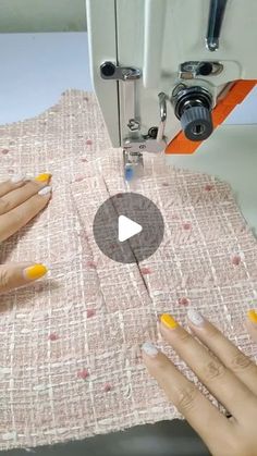 two hands using a sewing machine to sew on fabric with yellow and white nail polishes