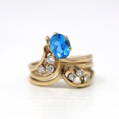 Stunning & unique vintage 14k yellow gold ring featuring a genuine swiss blue topaz gem. The asymmetrical ring contains 6 sparkling diamond accents, with an oval cut blue topaz weighing approximately 1.47 carats. A truly rare & one of a kind gemstone ring! ERA - Circa 1980s METAL / MATERIAL - 14k yellow gold, 1 genuine blue topaz gemstone (estimated 1.47 carats), 6 genuine diamonds (approx. .30 ctw, SI clarity range, near colorless) MARKINGS / HISTORY - Inside of band is stamped 14k COND Oval Blue Birthstone Ring For Anniversary, Blue Oval Birthstone Ring For Anniversary, Oval Topaz Ring In 14k Gold, 14k Gold Heirloom Oval Topaz Ring, Heirloom 14k Gold Oval Topaz Ring, Heirloom Oval Topaz Ring In 14k Gold, Vintage Blue Sapphire Ring Stamped 14k, Vintage Blue Gemstone Birthstone Ring, Vintage 14k Gold Topaz Birthstone Ring