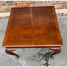 a wooden table sitting on top of a cement floor next to a brick wall in front of a building