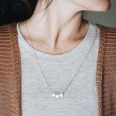 a close up of a person wearing a necklace with three small beads on the front