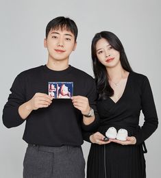 two people standing next to each other holding photos