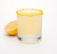 a glass filled with lemonade next to a slice of lemon