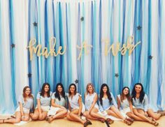 a group of women sitting next to each other in front of a blue and white backdrop