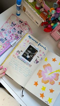 an open book on a table with markers, pens and other crafting supplies next to it