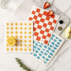 three placemats on a marble table with fruit and vegetables next to each other