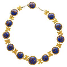 Lapis Necklace in 14k & 18K Gold. This Riviera styled necklace features 12 cabochon-cut lapis gemstones, each measuring 19–16 mm, and exhibits gold detailing within each stone, enhancing the royal blue hue. The necklace is crafted from 14K & 18K yellow gold, and surround each lapis stone with a textured design. The gold is also crafted into paisley art nouvea design between each stone, adding a feel of historical elegance to the piece. Comfortably sized at 17 inches and weighing 71.02 grams, this substantial chain necklace is a perfect gift to add to your jewelry collection. Item Details: - Type: Necklace - Metal: 14K Yellow Gold, 18K Yellow Gold - Weight: 71.02 grams - Setting: Bezel - Size: 17 inches _______________________ Stone Details: - Lapis: 12 Cabochon cut Lapis, 19-16mm (each) __