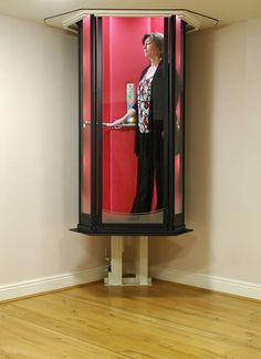 a woman is standing in the corner of a room with a red wall behind her