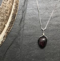 Protection Stone Necklace, Gemstone Protection Jewelry, Garnet Necklace, Empath Protection Gemstone Jewelry This unique handmade, crystal gemstone necklace is a wonderful addition to any wardrobe. This deep red, gemstone pendant is an all natural Garnet nugget with unique textures. The gemstone is wire wrapped in genuine sterling silver and is carried by a box style chain. A spring ring clasp secures the chain. All together creating a perfect necklace for everyday wear. About the Gemstone: Garne Red Garnet Oval Pendant Necklace, Red Crystal Pendant Necklace With Natural Stones, Red Natural Stone Crystal Pendant Necklace, Ruby Gemstone Teardrop Pendant Necklace, Red Gemstone Pendant Crystal Necklaces, Red Pendant Crystal Necklaces With Gemstone, Red Gemstone Pendant Crystal Necklace, Red Spiritual Pendant Crystal Necklaces, Red Crystal Pendant Necklaces