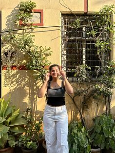 a woman standing in front of a building talking on a cell phone while wearing white pants