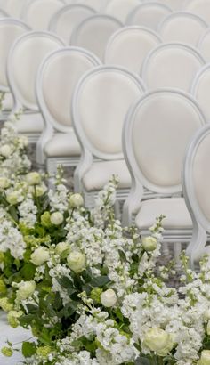 rows of white chairs with flowers on them