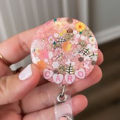 a person holding a badge with buttons and flowers on it that says caro in pink