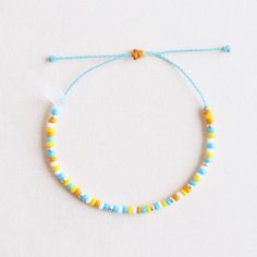 a blue string bracelet with yellow and white beads