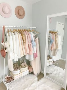 a closet with clothes and hats hanging on the rack, next to a large mirror