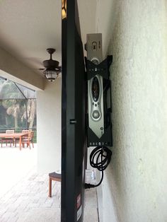 an old style phone is hanging on the wall next to a patio table and chairs