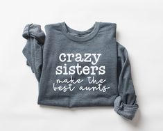 Crazy Sisters Make the Best Aunts, Aunt Sweatshirt, Funny Sister Gift, Sister Auntie Shirt, Aunt Sweater, Aunt Announcement Gift This crewneck sweatshirt is pure comfort. Made from a soft cotton/poly blend with no itchy side seams, this is sure to become a staple. SIZE AND FIT: Your sweatshirt design will be printed on a high-quality, soft and comfortable unisex sweatshirt. Sizes run true to size, which takes the guesswork out of ordering; if you like your sweatshirts loose or oversized, you might want to order a size up and if you'd like a more fitted women's style then order a size down. Sizes range from S - 3X. Please refer to our size chart in the photos for exact dimensions. DETAILS AND FABRIC: * 50% Cotton 50% Polyester * Medium-heavy fabric (8.0 oz/yd² (271.25 g/m * Loose Unisex Fit Winter Cotton Tops With Funny Text, Aunt Announcement, Aunt Sweater, Funny Sister Gifts, Funny Sister, Aunt Sweatshirt, Crazy Sister, Auntie Shirts, Best Aunt