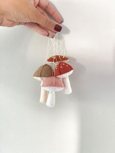 a person holding onto some small mushrooms hanging from strings on a wall with their hands