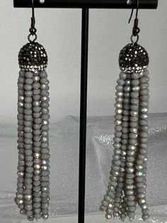 Sterling Grey Polished Beaded Tassel Earrings feature a cascading design of delicate, polished grey beads, creating an elegant and fluid tassel effect. These earrings are anchored by a sterling silver top, adding a touch of sophistication and shine to the overall design. Elegant Silver Long Drop Tassel Earrings, Elegant Silver Earrings With Tassels, Silver Fringe Long Drop Earrings, Silver Long Drop Tassel Earrings With Fringe, Gray Beaded Dangle Earrings, Silver Tassel Earrings For Evening, Elegant Silver Tassel Earrings With Dangling Beads, Silver Dangle Tassel Earrings, Silver Dangle Tassel Earrings With Fringe