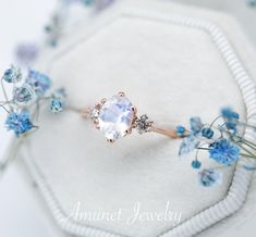 an engagement ring with a large white stone surrounded by blue flowers