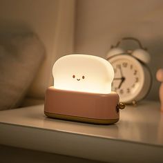 an alarm clock sitting on top of a table next to a toaster shaped like a face