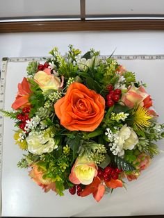 a bouquet of flowers sitting on top of a white table next to a measuring ruler