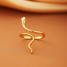 Embrace the timeless elegance and symbolism of our Snake Ring collection. These stunning rings, are designed to add a touch of sophistication and mystique to any outfit. Features: Material: High-quality silver with a luxurious gold plating, ensuring durability and a beautiful shine. Design: The ring features a smooth, vintage-inspired snake design that wraps gracefully around your finger. Its minimalist style makes it perfect for stacking or wearing solo as a statement piece. Adjustable Fit: The Adjustable Minimalist Snake Ring, Minimalist Adjustable Open Snake Ring, Symbolic Open Snake Promise Ring, Minimalist Snake Ring For Anniversary, Elegant Snake Shape Ring As Gift, Elegant Snake Shape Ring Gift, Minimalist Sterling Silver Snake Ring, Elegant Snake Shape Ring For Gift, Minimalist Yellow Gold Snake Ring